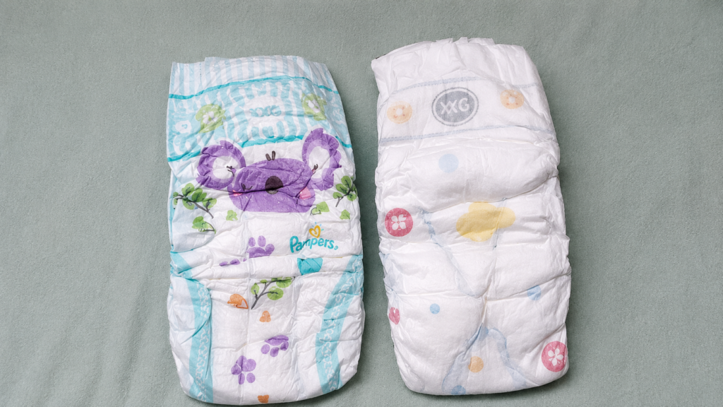 fralda da pampers e fralda huggies sobre um lençol 