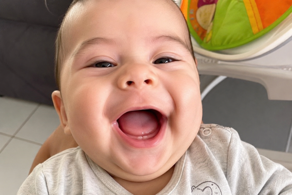Bebê sorrindo mostrando a gengiva com os primeiros dentinhos nascendo.